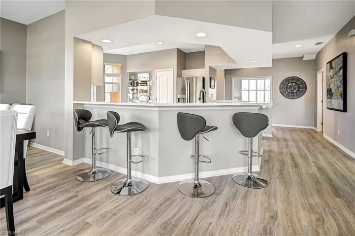 Kitchen featuring kitchen peninsula, light hardwood / wood-style floors, stainless steel refrigerator with ice dispenser, and a breakfast bar