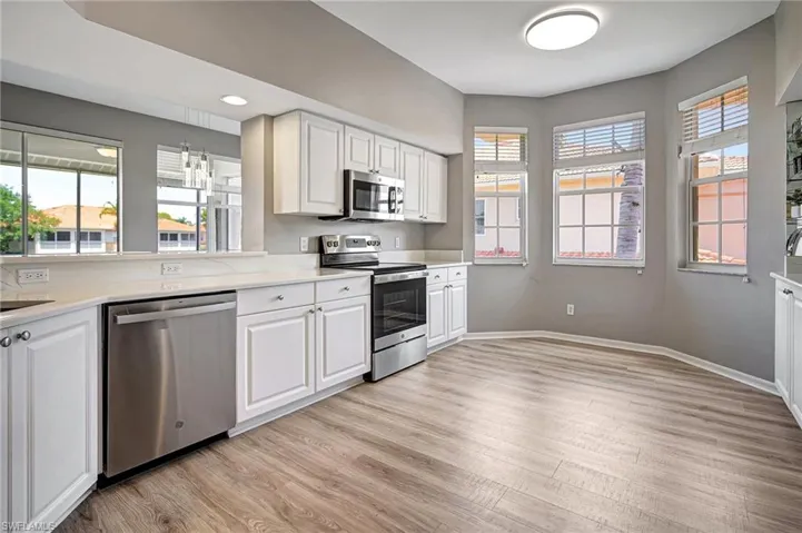 Kitchen featuring pendant lighting, white cabinetry, stainless steel appliances, and light wood-type flooring