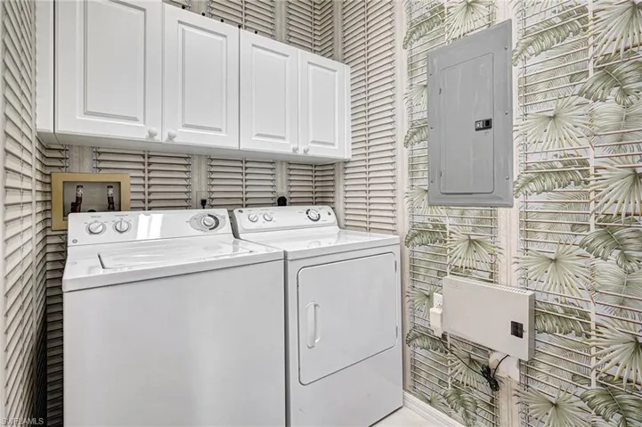 Laundry area with cabinets, electric panel, and washing machine and dryer