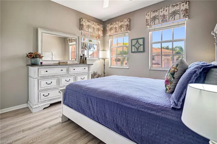 Bedroom featuring ceiling fan, multiple windows, and light wood-type flooring