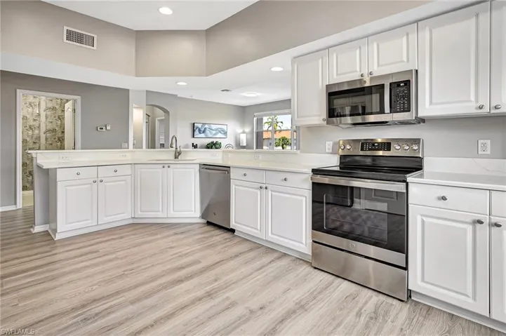 Kitchen featuring light hardwood / wood-style floors, white cabinets, sink, kitchen peninsula, and stainless steel appliances