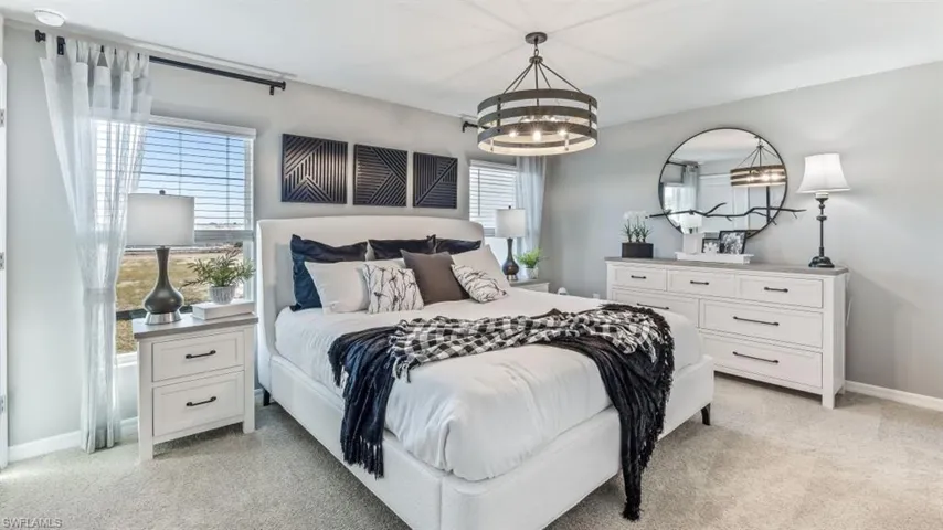 Carpeted bedroom featuring an inviting chandelier and multiple windows