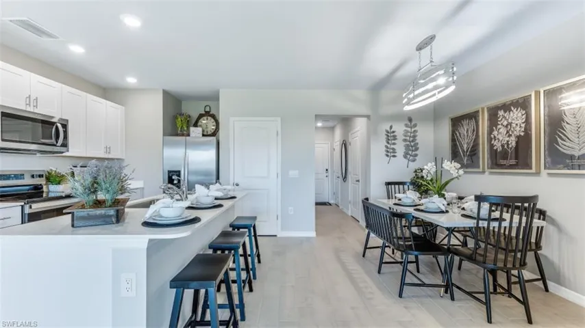 Kitchen featuring stainless steel appliances, sink, pendant lighting, light hardwood / wood-style floors, and white cabinetry