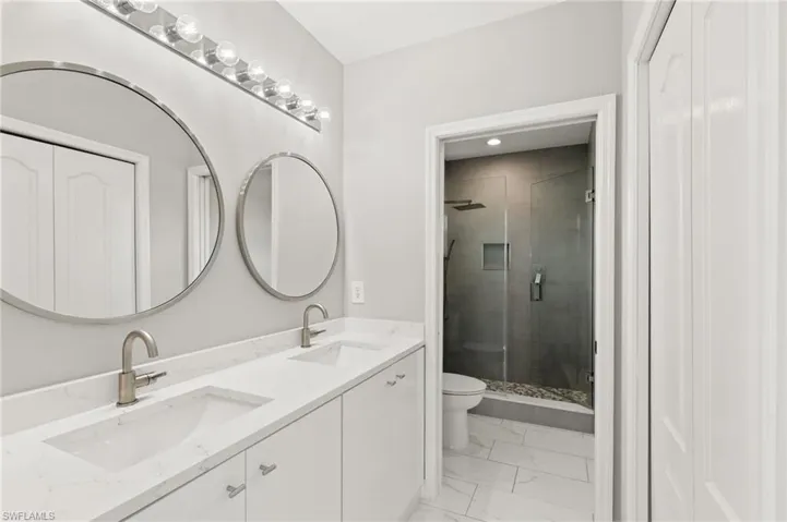 The primary ensuite bath is a modern luxury spa with dual sinks, circular mirrors, and lacquer vanities.