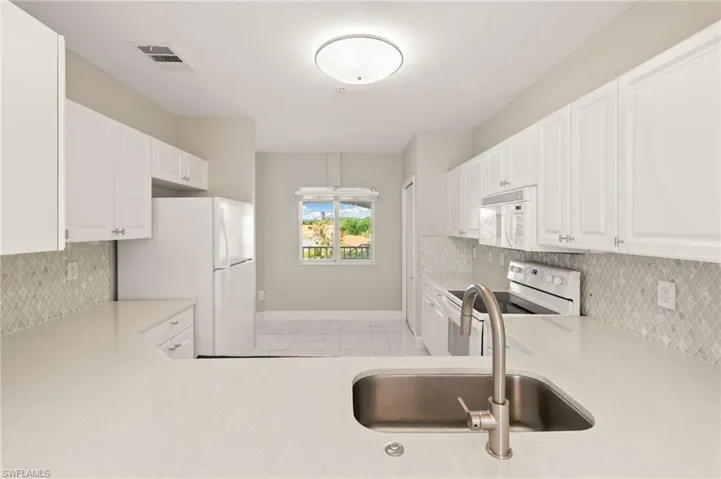 Fully renovated kitchen with quartz countertops, glass backsplash and an excess amount of countertop space and cabinetry!