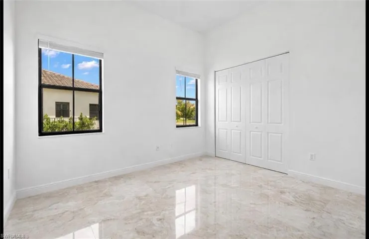 Unfurnished bedroom featuring light marble finish floors and a closet