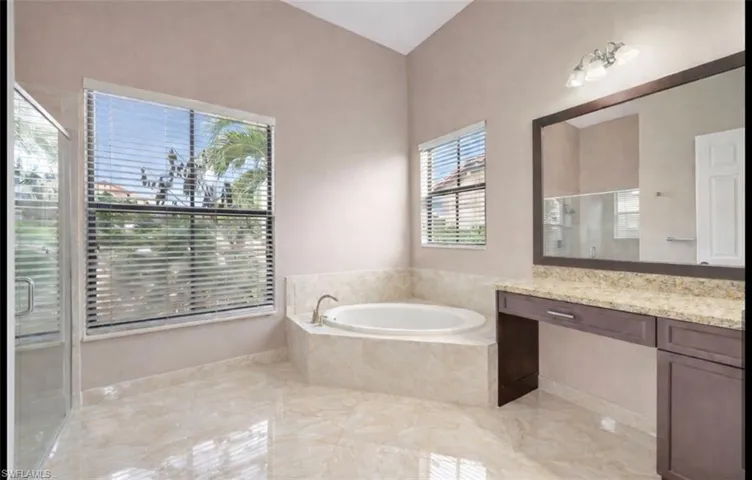 Full bath with a shower stall, a garden tub, vanity, and light marble finish floors