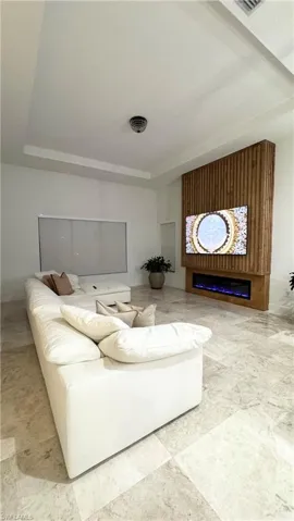 Living area with a tray ceiling and a glass covered fireplace