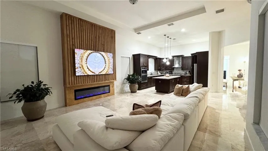 Living area featuring a glass covered fireplace, recessed lighting, and light marble finish flooring