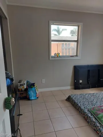 Bedroom with light tile patterned flooring, crown molding, and baseboards