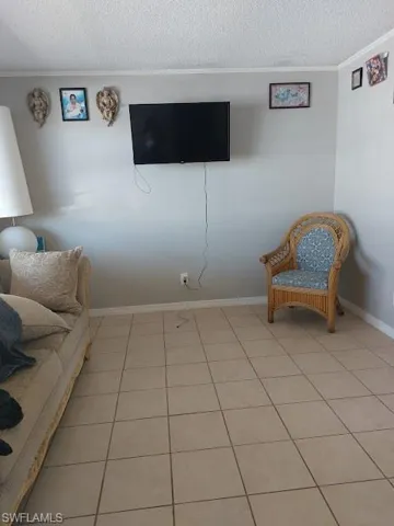 Sitting room featuring crown molding, a textured ceiling, light tile patterned floors, and baseboards