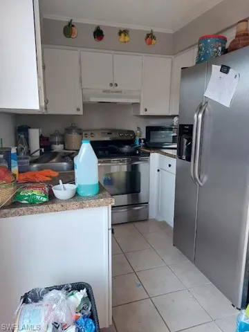Kitchen with appliances with stainless steel finishes, under cabinet range hood, a sink, white cabinets, and ornamental molding