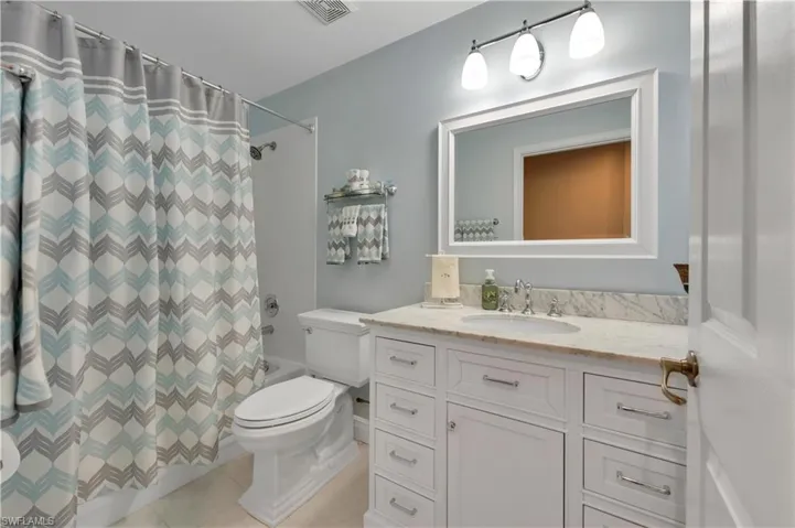 Full Guest Bath featuring vanity, shower / bath combo, and light tile patterned flooring