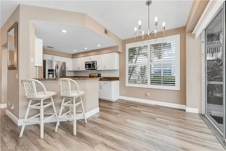 Kitchen with stainless steel appliances, recessed lighting, pendant lighting, white cabinets, and a chandelier