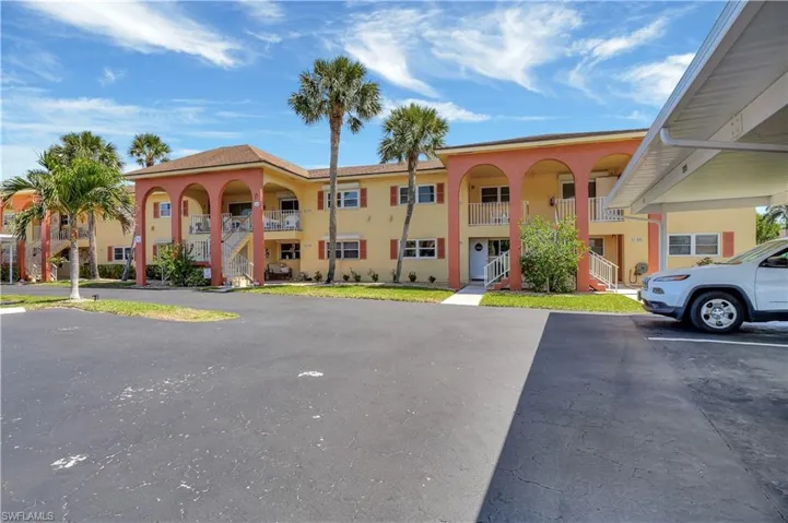View of property featuring covered and uncovered parking