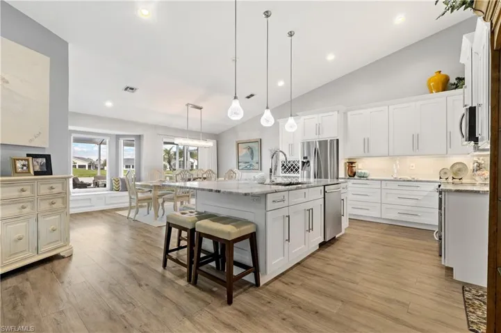 Kitchen featuring white cabinetry, hanging light fixtures, sink, and a center island with sink