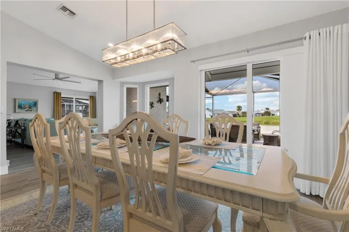 Dining space with lofted ceiling, hardwood / wood-style floors, and ceiling fan with notable chandelier