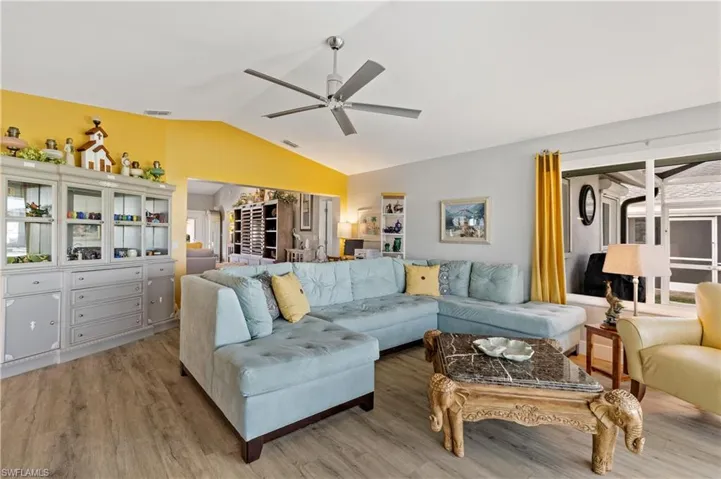 Living room featuring vaulted ceiling, ceiling fan, and light wood-type flooring