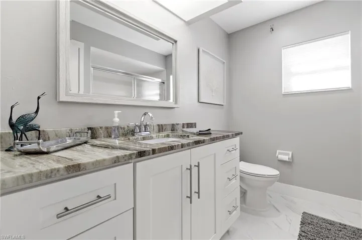 Bathroom featuring a shower with door, vanity, and toilet