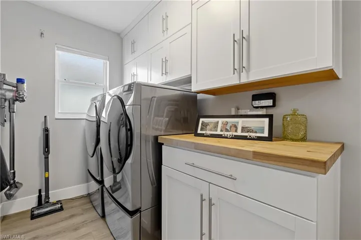 Laundry area with cabinets, washing machine and dryer, and light hardwood / wood-style floors