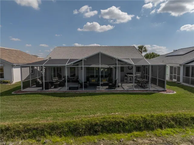 Rear view of property with a patio area, a lawn, and glass enclosure