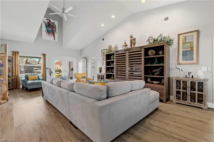 Living room featuring high vaulted ceiling, french doors, ceiling fan, and light wood-type flooring