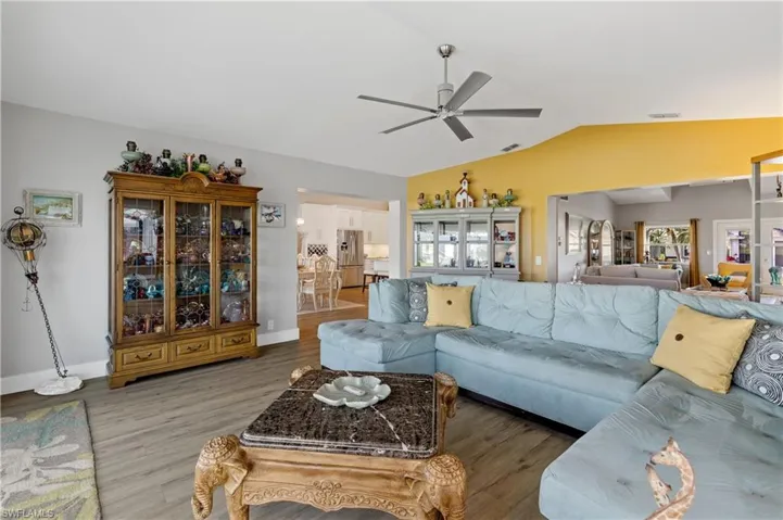 Living room with lofted ceiling, hardwood / wood-style floors, and ceiling fan