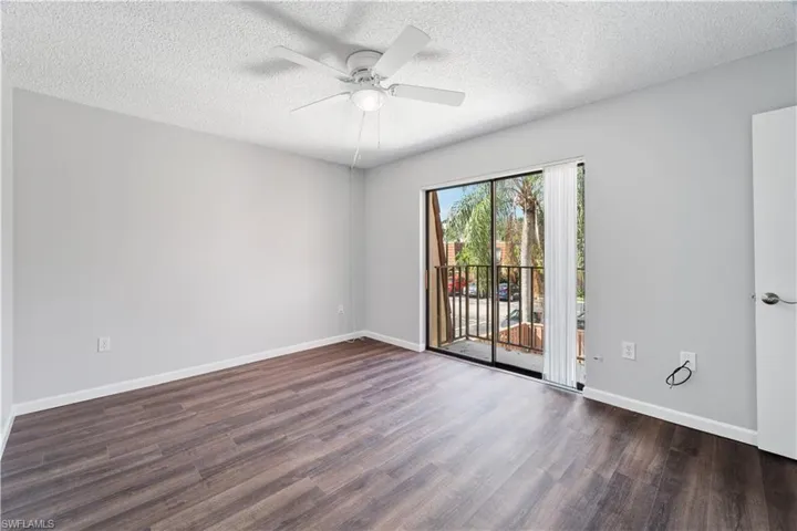 Unfurnished room featuring ceiling fan, baseboards, a textured ceiling, and wood finished floors