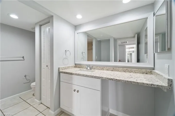 Bathroom featuring vanity, a closet, baseboards, tile patterned flooring, and toilet