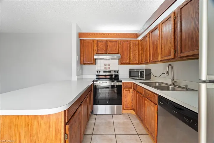 Kitchen featuring light countertops, a peninsula, appliances with stainless steel finishes, and a sink