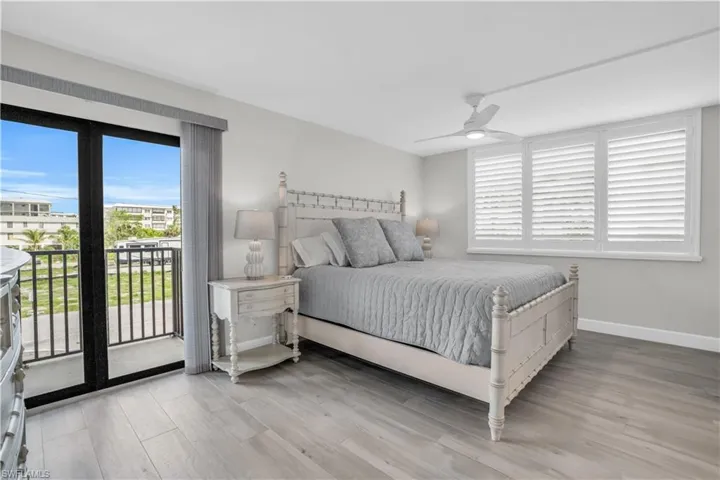 Primary bedroom with hardwood / wood-style floors, ceiling fan, and access to exterior