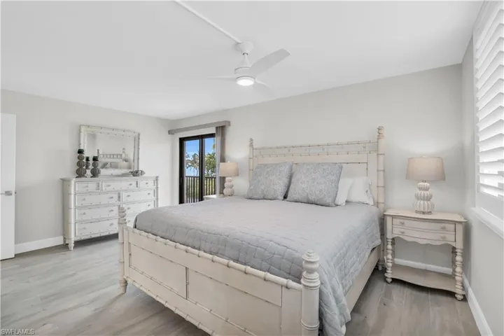 Primary bedroom with ceiling fan, light hardwood tile / wood-style flooring, and access to exterior