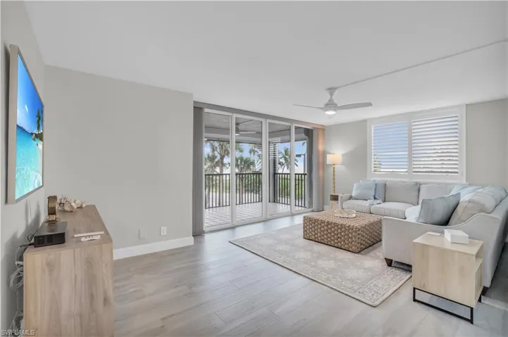 Living room with ceiling fan, a wall of windows, and hardwood / wood-style floors