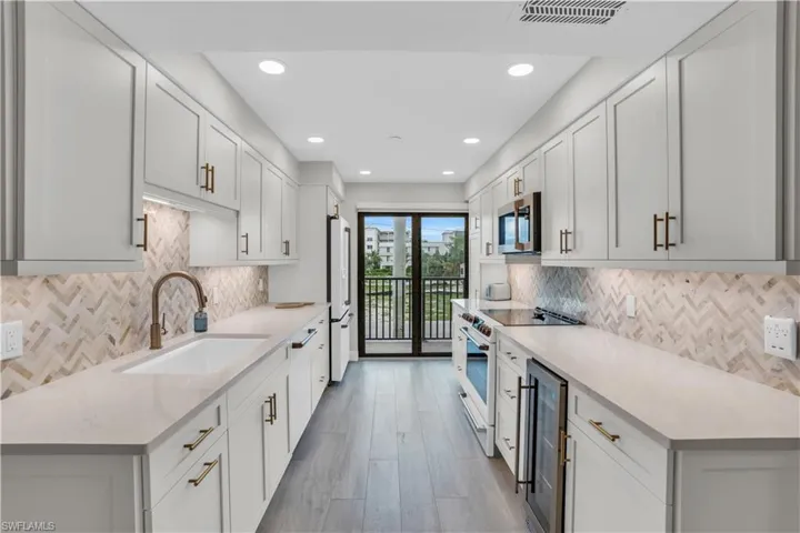 Kitchen with beverage cooler, white appliances, sink, and tasteful backsplash
