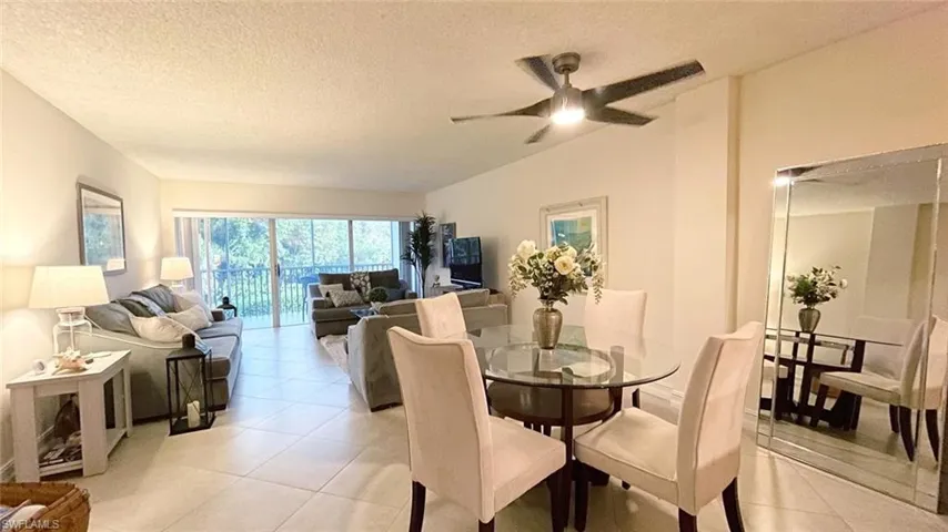 Dining room with light tile patterned floors, ceiling fan, a textured ceiling, and vaulted ceiling