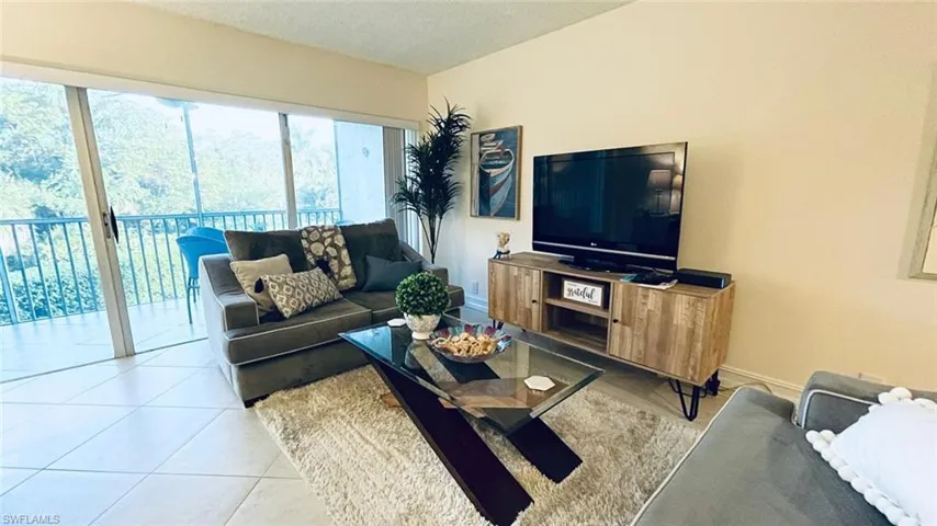 Tiled living room with a textured ceiling and baseboards