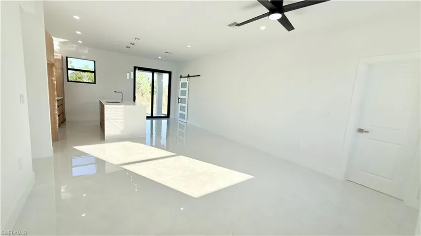 Empty room featuring recessed lighting, ceiling fan, and a barn door
