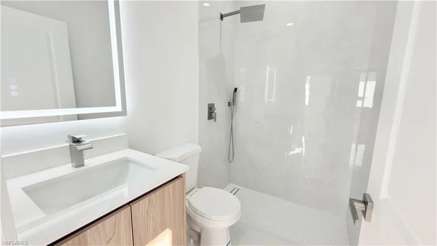 Bathroom with vanity and a marble finish shower