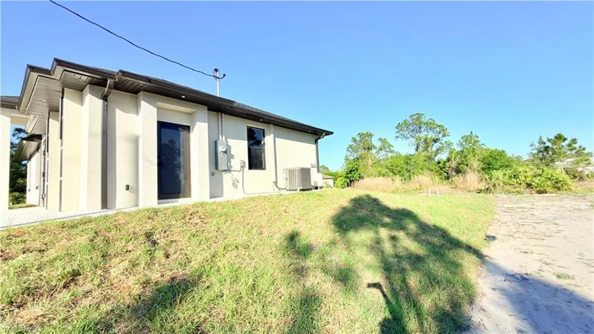 Back of house featuring stucco siding and a yard