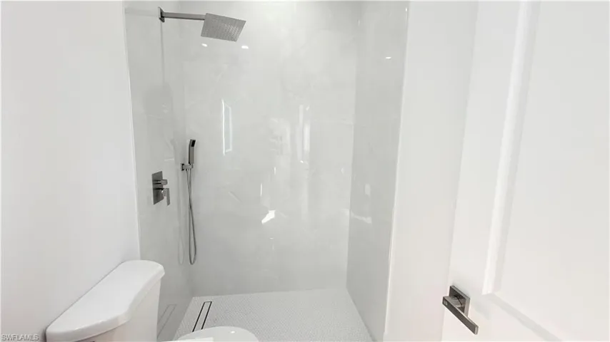 Full bathroom featuring toilet and a marble finish shower