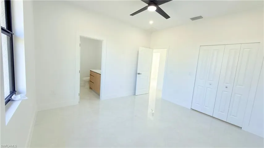 Unfurnished bedroom with a ceiling fan, ensuite bath, and a closet