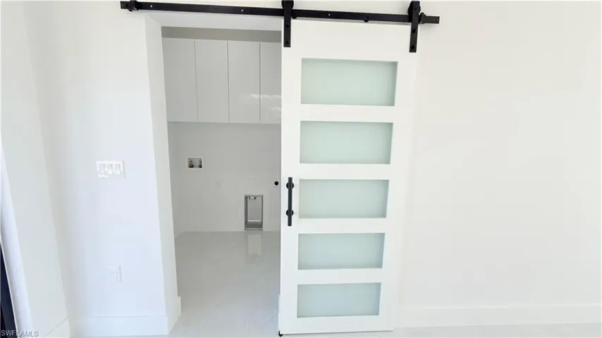 Laundry room featuring a barn door, built in shelves, and washer hookup