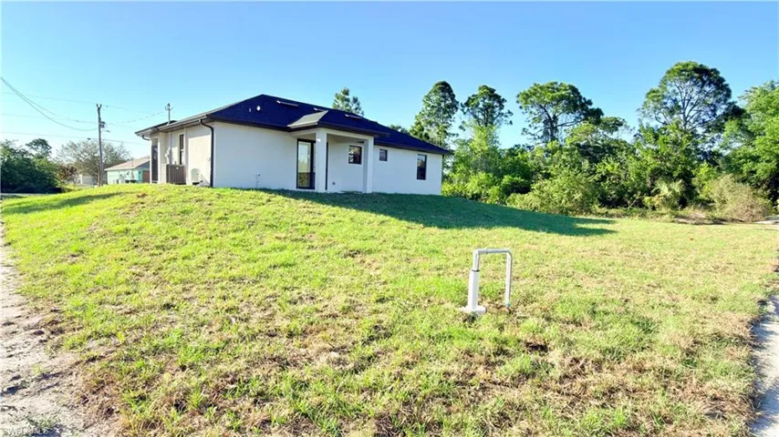 Back of house with stucco siding and a lawn