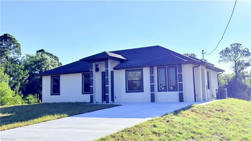 View of front of home with stucco siding, a front lawn, and a shingled roof