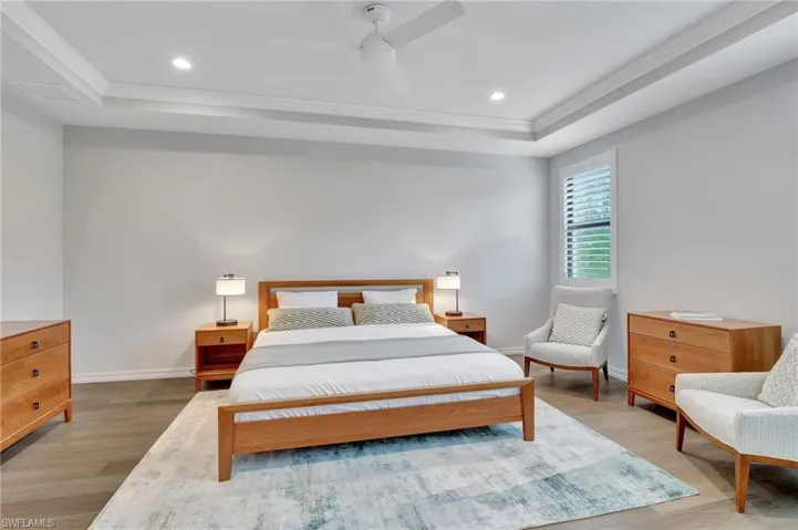 Bedroom featuring a raised ceiling, ceiling fan, light hardwood / wood-style floors, and ornamental molding