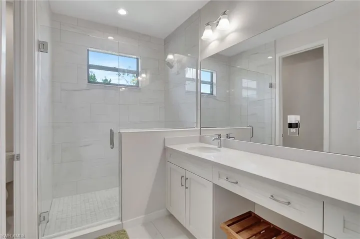 Bathroom featuring tile patterned floors, vanity, and an enclosed shower