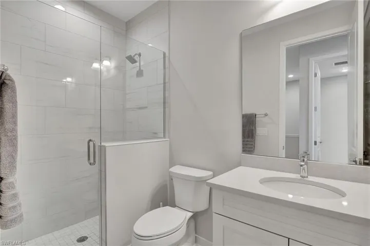 Bathroom featuring vanity, toilet, and a shower with door