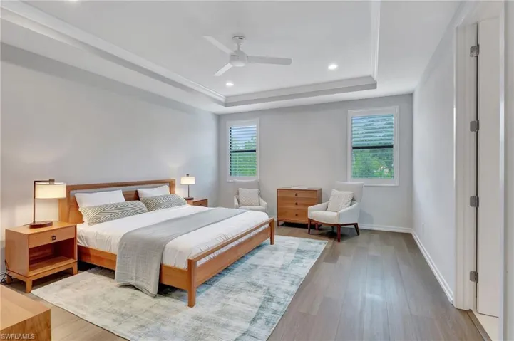Bedroom featuring ceiling fan, a raised ceiling, and light hardwood / wood-style flooring