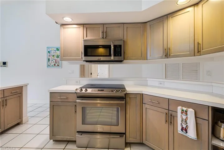 Kitchen featuring baseboards, light tile patterned flooring, recessed lighting, stainless steel appliances, and light countertops