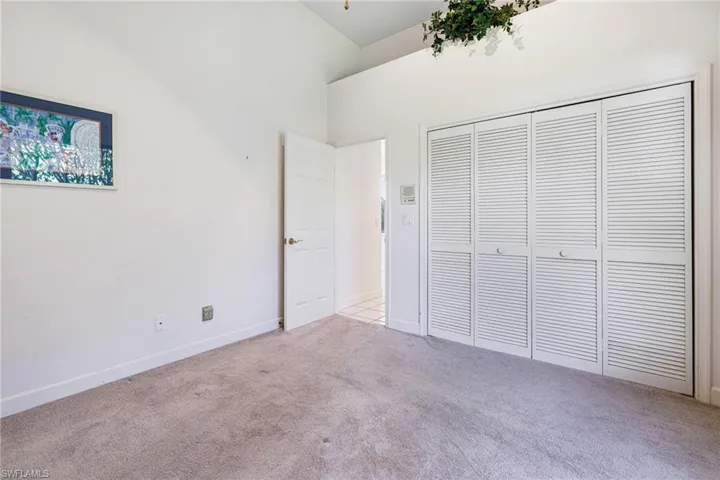 Unfurnished bedroom with a closet, carpet flooring, baseboards, and vaulted ceiling